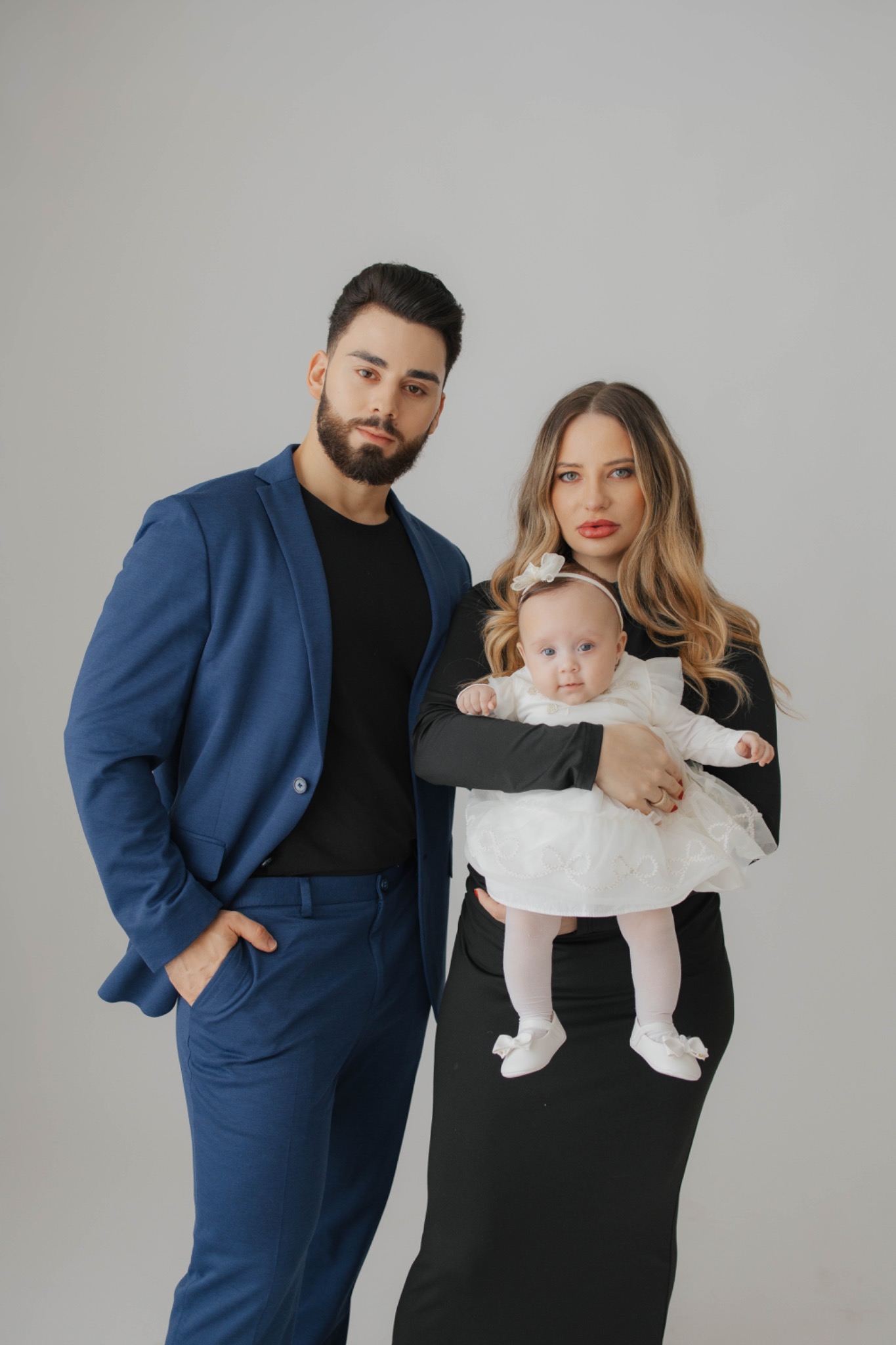 Yuri Peloi com sua família em fotografia de estúdio, usando blazer azul